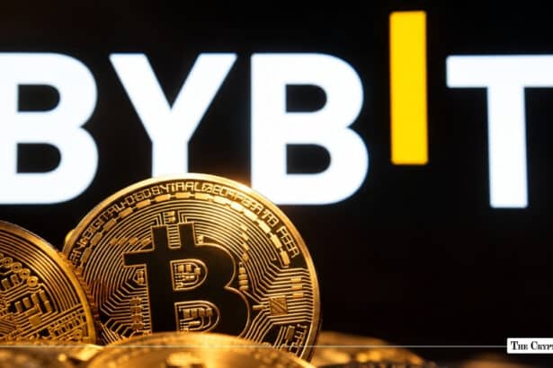 Physical gold Bitcoin coins in front of a brightly lit white and yellow Bybit logo on a dark background.