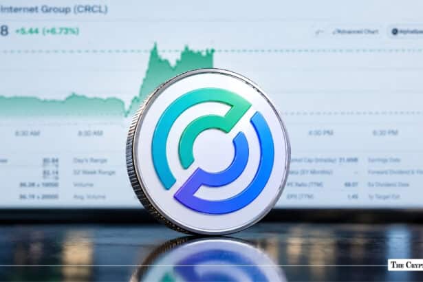 Physical Circle (USDC) coin standing in front of a stock market performance screen.