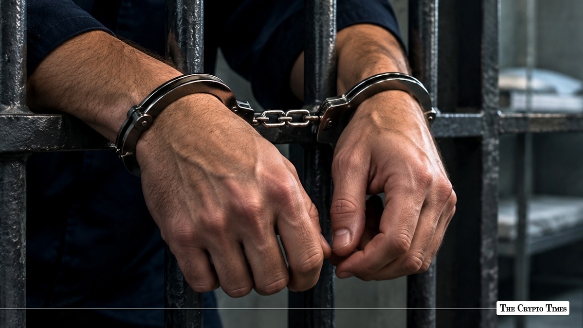 Close-up of a person's handcuffed hands resting against the dark metal bars of a jail cell