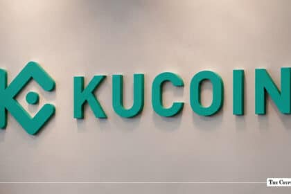 Green KuCoin logo and wordmark mounted on a off-white corporate wall.