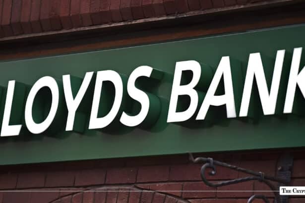 White dimensional Lloyds Bank signage mounted on a green storefront fascia over brickwork