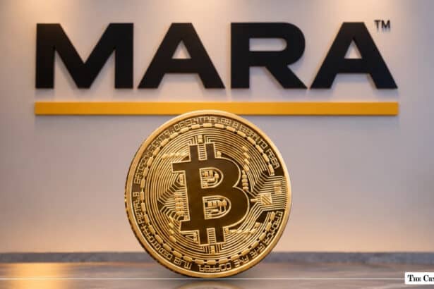 Physical gold Bitcoin coin in front of a MARA corporate logo
