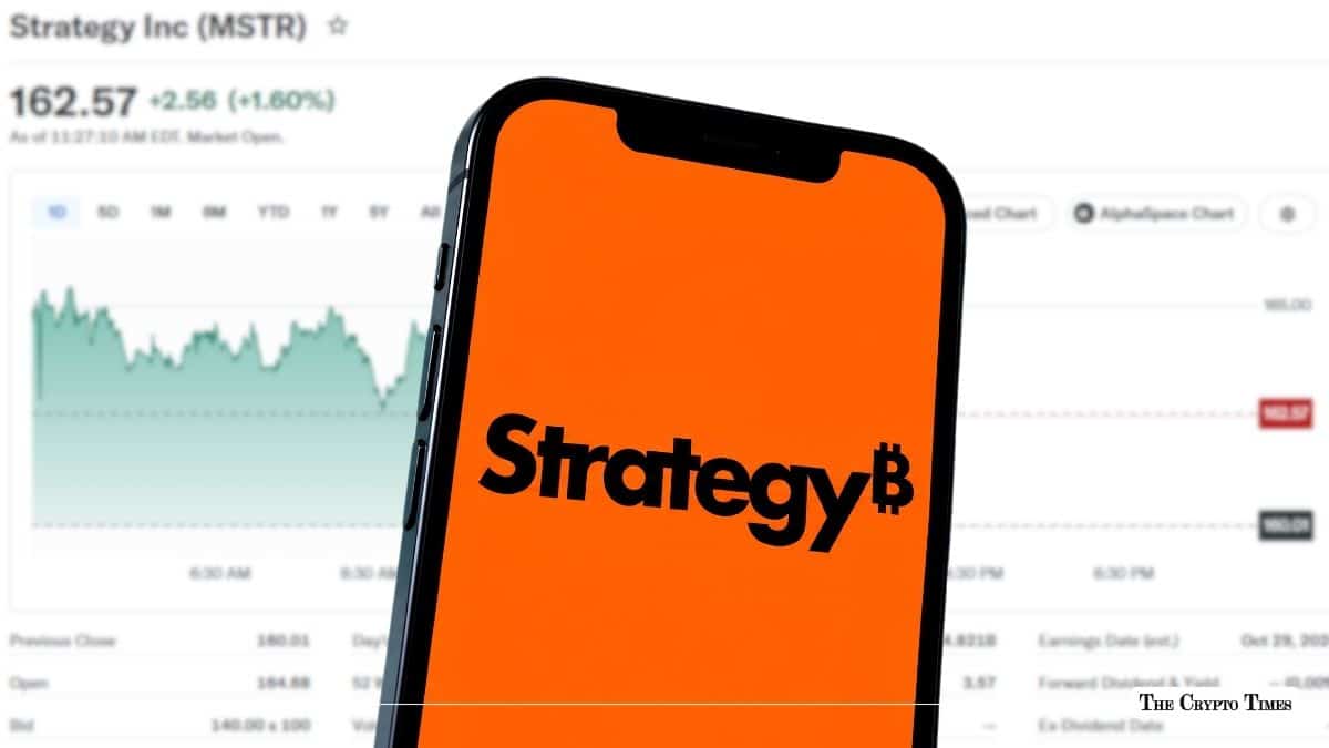 Smartphone displaying the MicroStrategy "Strategy" logo on an orange background in front of a stock market price chart.