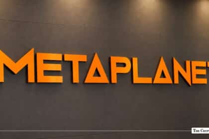 Orange 3D Metaplanet logo mounted on a dark grey corporate office wall