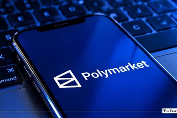 Smartphone displaying the Polymarket logo resting on a laptop keyboard.