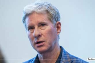 Close-up portrait of Ripple co-founder and executive chairman Chris Larsen wearing a blue plaid jacket speaking