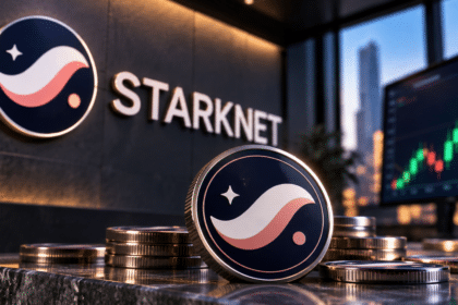 Physical Starknet token coin standing in an office with Starknet wall signage and a trading screen.