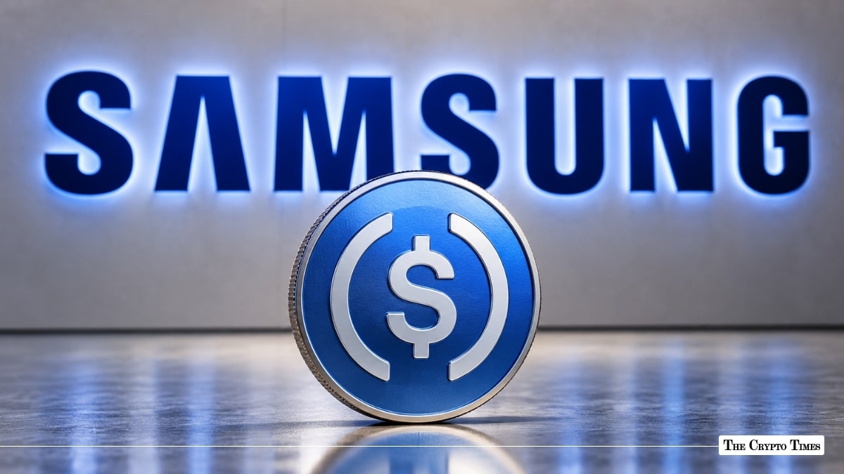 Physical USD Coin (USDC) token standing in front of an illuminated Samsung corporate wall sign