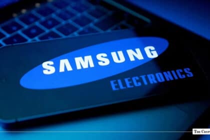 Smartphone screen displaying the Samsung Electronics logo resting on a illuminated laptop keyboard