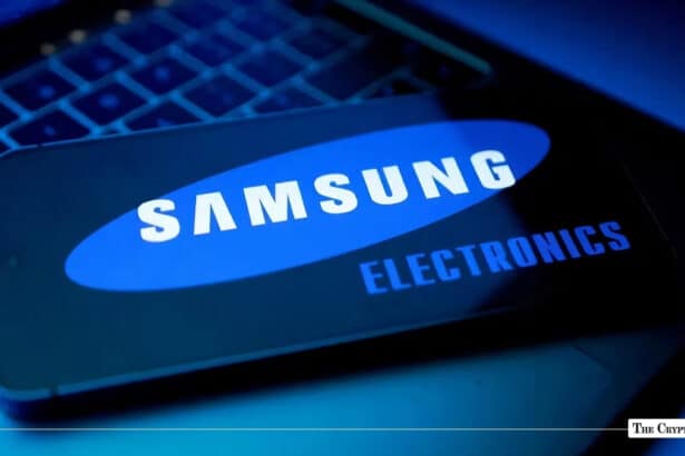 Smartphone screen displaying the Samsung Electronics logo resting on a illuminated laptop keyboard