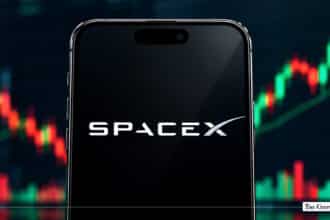 Smartphone displaying the SpaceX logo in front of a stock market candlestick chart.