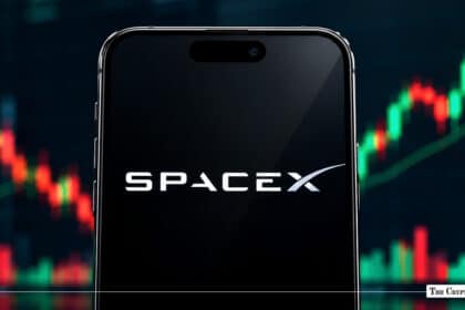 Smartphone displaying the SpaceX logo in front of a stock market candlestick chart.