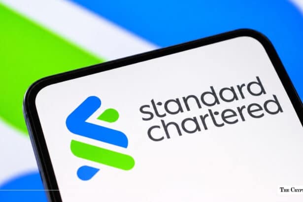Smartphone screen displaying the blue and green Standard Chartered logo and wordmark against a blurred corporate backdrop