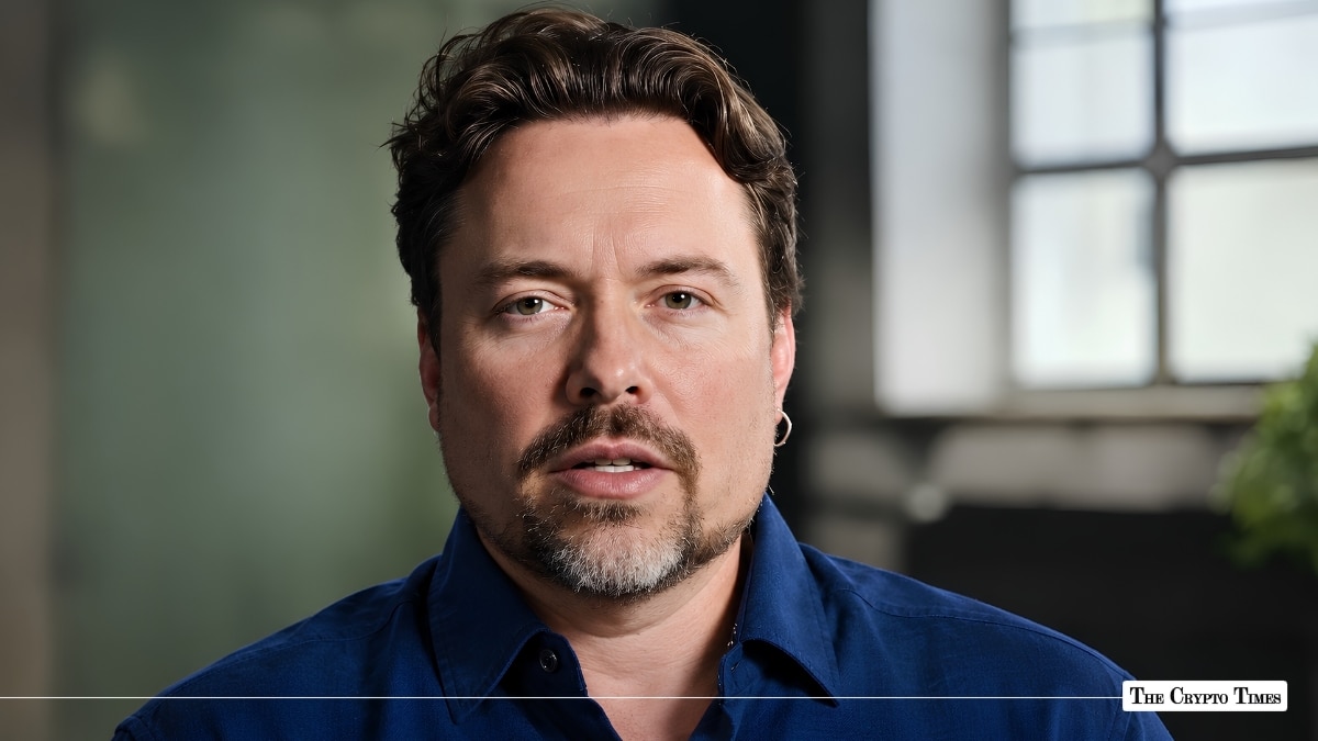 Portrait of a man with dark wavy hair, a goatee, and a blue collared shirt.