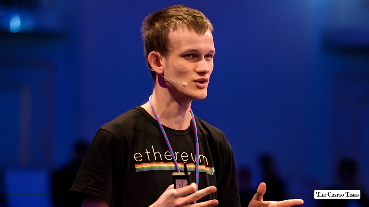Ethereum co-founder Vitalik Buterin gesturing while speaking on stage in a black Ethereum t-shirt against a dark blue background