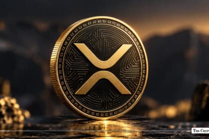 Physical gold XRP token standing on a dark reflective surface against a rugged landscape background